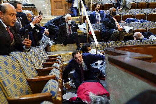 People shelter in the House gallery as rioters try to break into the House Chamber at the U.S. Capitol on Wednesday, Jan. 6, 2021, in Washington. (AP Photo/Andrew Harnik)